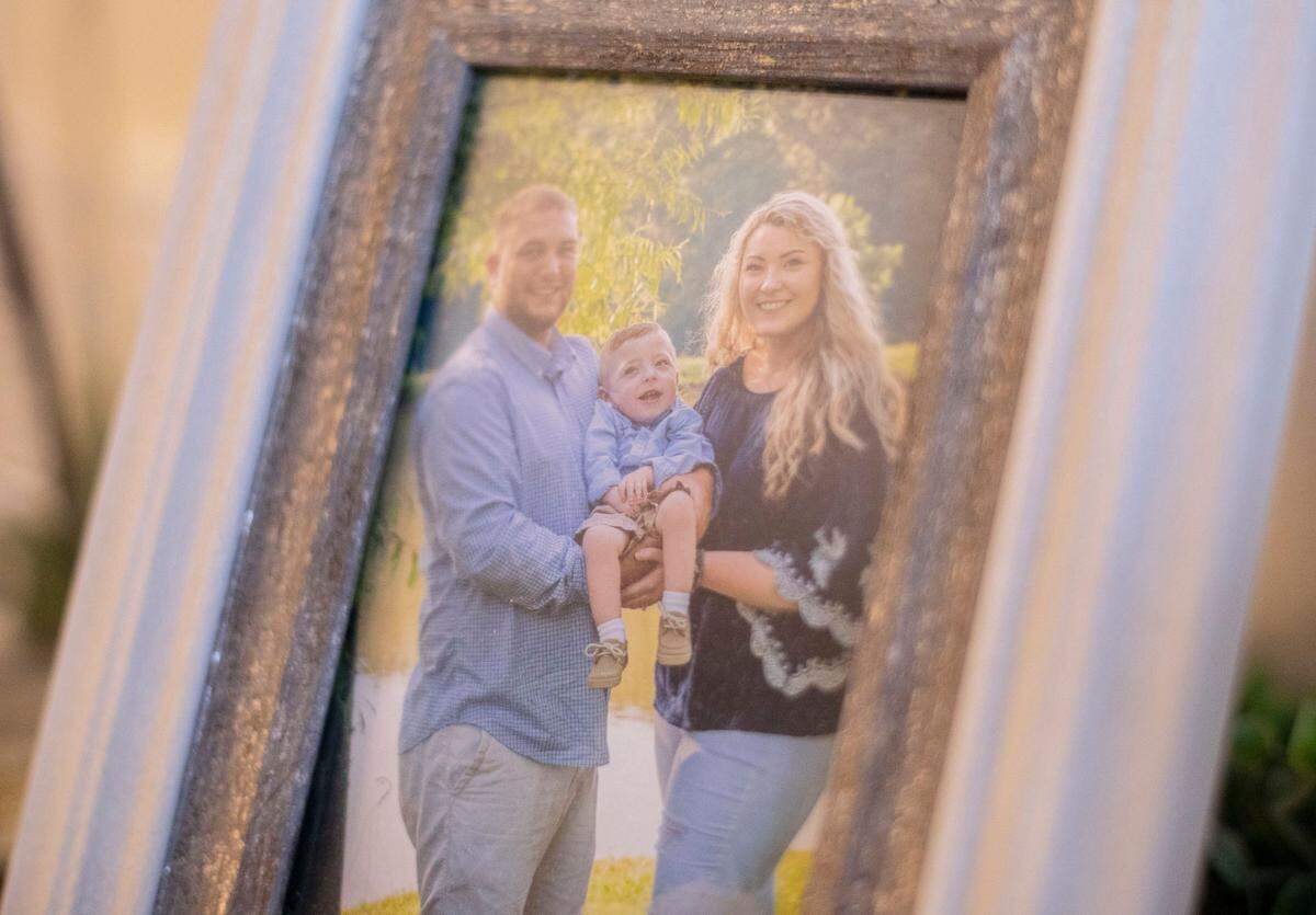 Michael Yannotti, left, and Claudia Moore, right, are seen holding their son Boston Yannotti, 5, in a framed photograph in their home in Eden, N.C. on March 9, 2022.