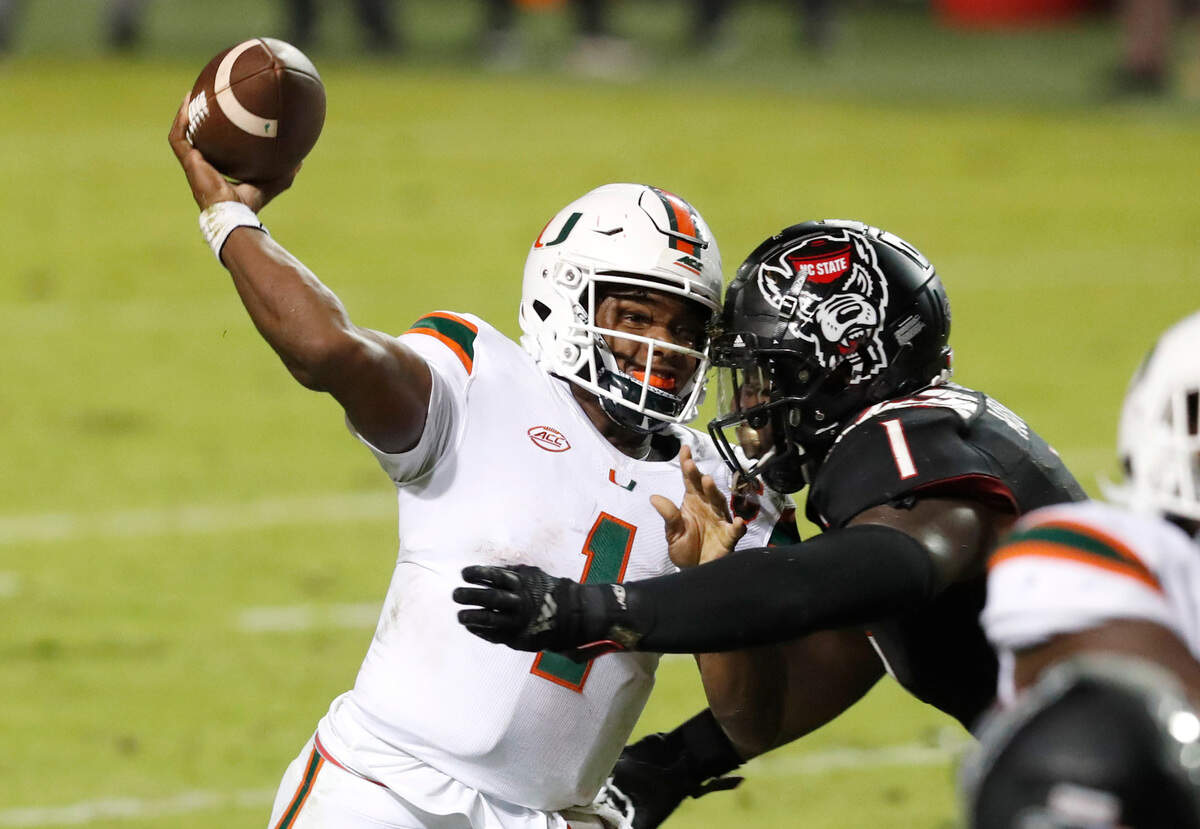 Miami quarterback D’Eriq King (1) passes as N.C. State linebacker Isaiah Moore (1) pressures him during the second half of Miami’s 44-41 victory over N.C. State at Carter-Finley Stadium in Raleigh, N.C., Friday, Nov. 6, 2020.