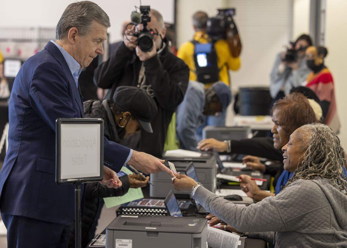 Former NC governor and U.S. Senate candidate Roy Cooper shows his ID before receiving his ballot to vote, on the first day of early voting in the North Carolina primary, on Thursday, Feb. 12, 2026 in Raleigh, N.C. 