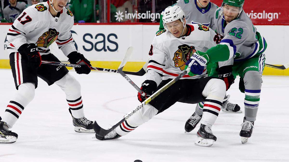 Carolina Hurricanes’ Brett Pesce (22) reaches in to tip the puck away from Chicago Blackhawks’ Philipp Kurashev (23) with Blackhawks’ Dylan Strome (17) nearby during the first period of an NHL hockey game in Raleigh, N.C., Friday, Feb. 19, 2021. (AP Photo/Karl B DeBlaker)