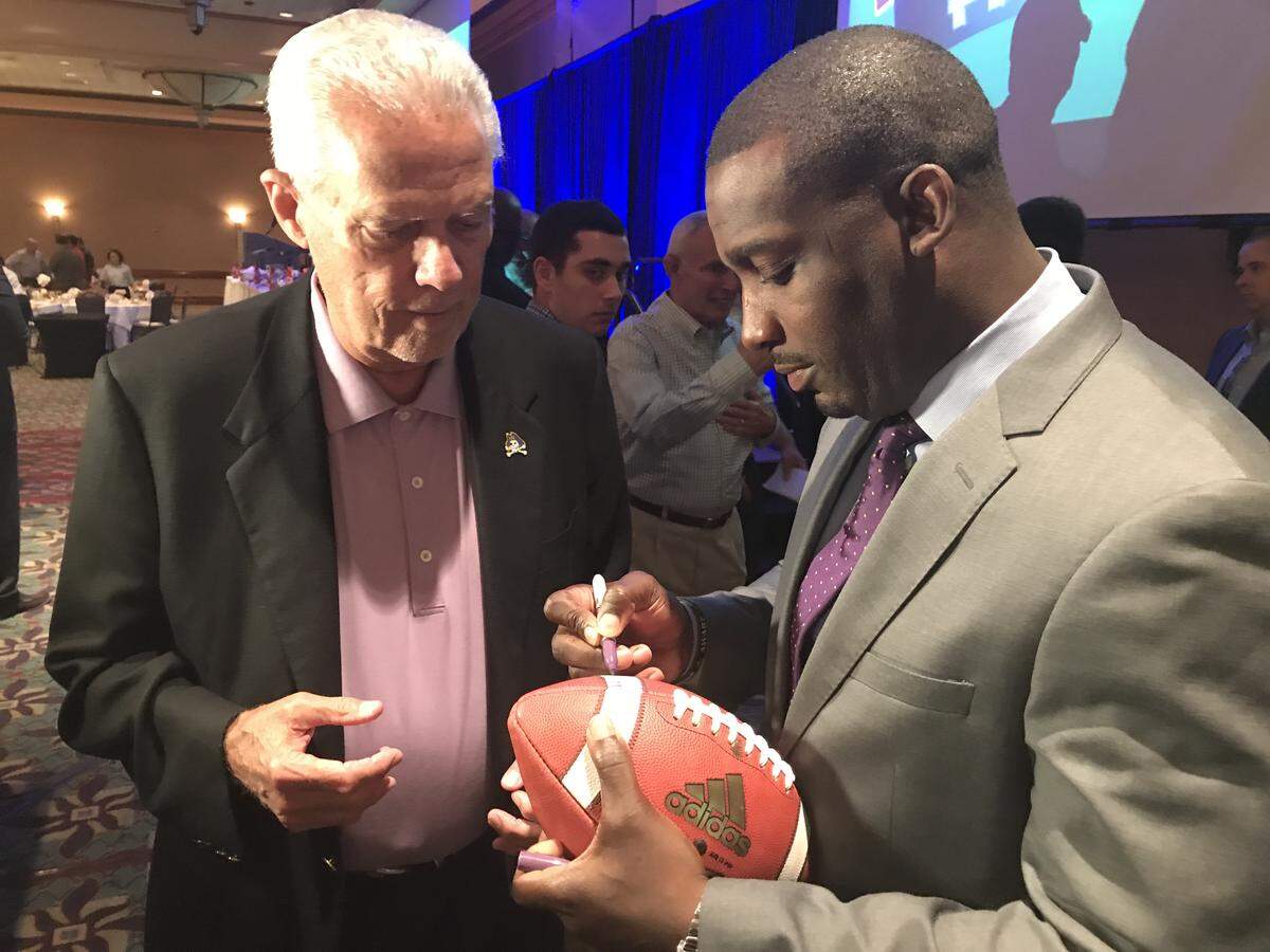 East Carolina coach Scottie Montgomery signs a football for an ECU fan after his Pigskin Preview appearance in Cary on July 16, 2018.
