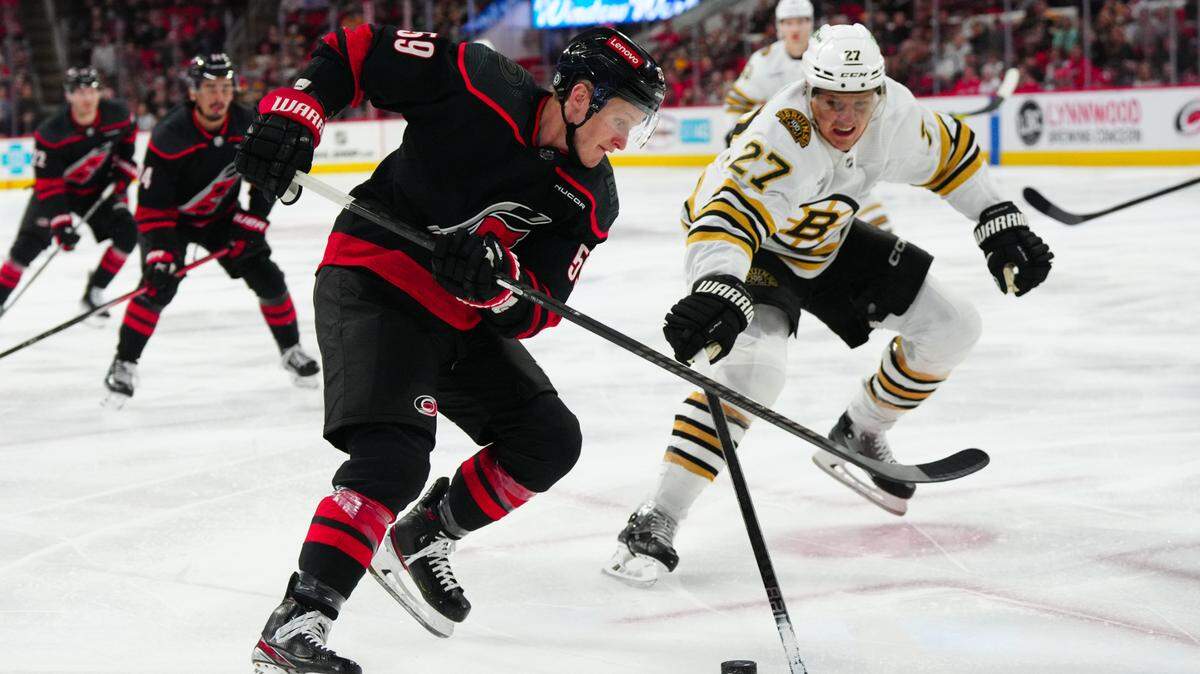 Carolina Hurricanes left wing Jake Guentzel (59) skates with the puck against Boston Bruins defenseman Hampus Lindholm (27) during the first period at PNC Arena.