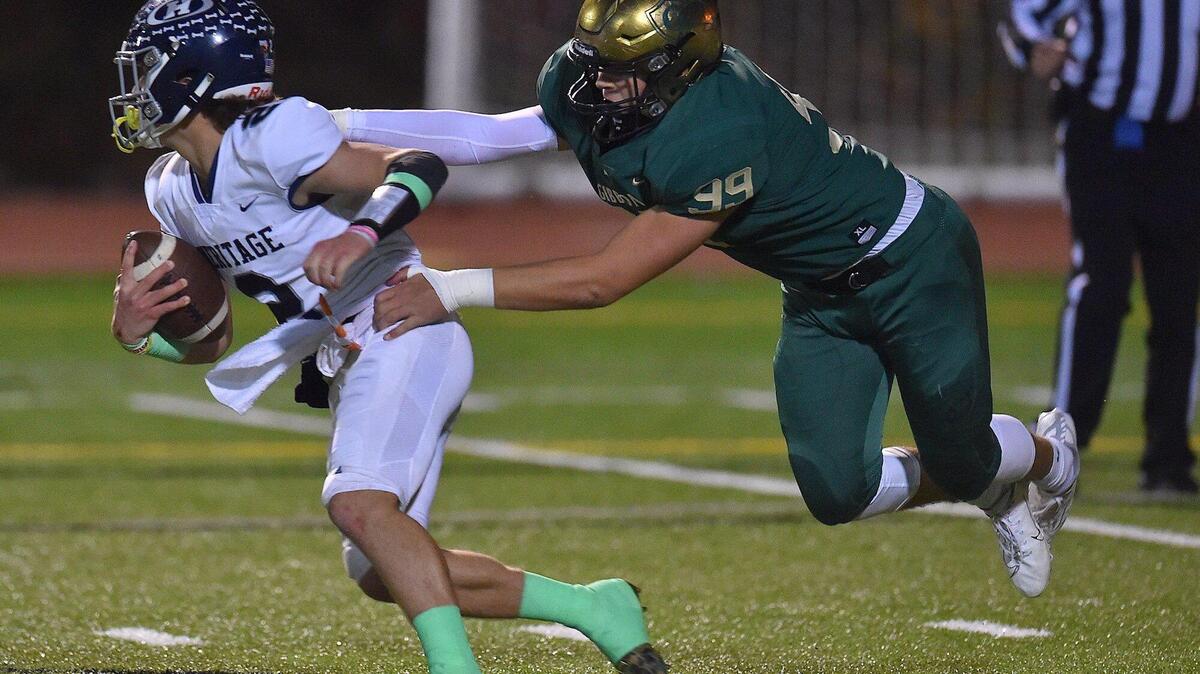Heritage quarterback Lex Thomas (2) evades the tackle from Cardinal Gibbons’ Joshua Stoneking (99) during the first half. The Heritage Huskies and the Cardinal Gibbons Crusaders met in a NCHSAA 4A playoff game in Raleigh, N.C. on November 12, 2021