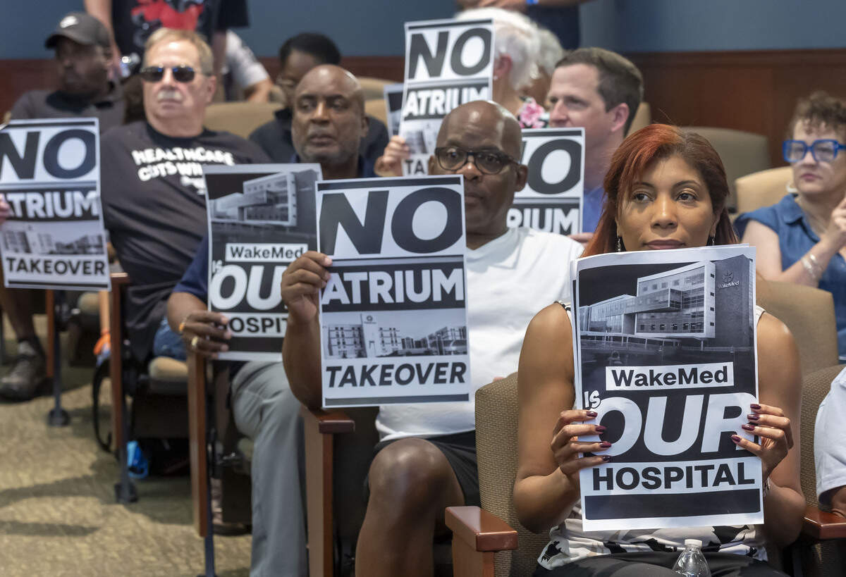 Opponents of a proposed merger between WakeMed and Atrium Health display their position before the Wake County Commissioners meeting on Monday, July 6, 2026, in Raleigh, N.C.