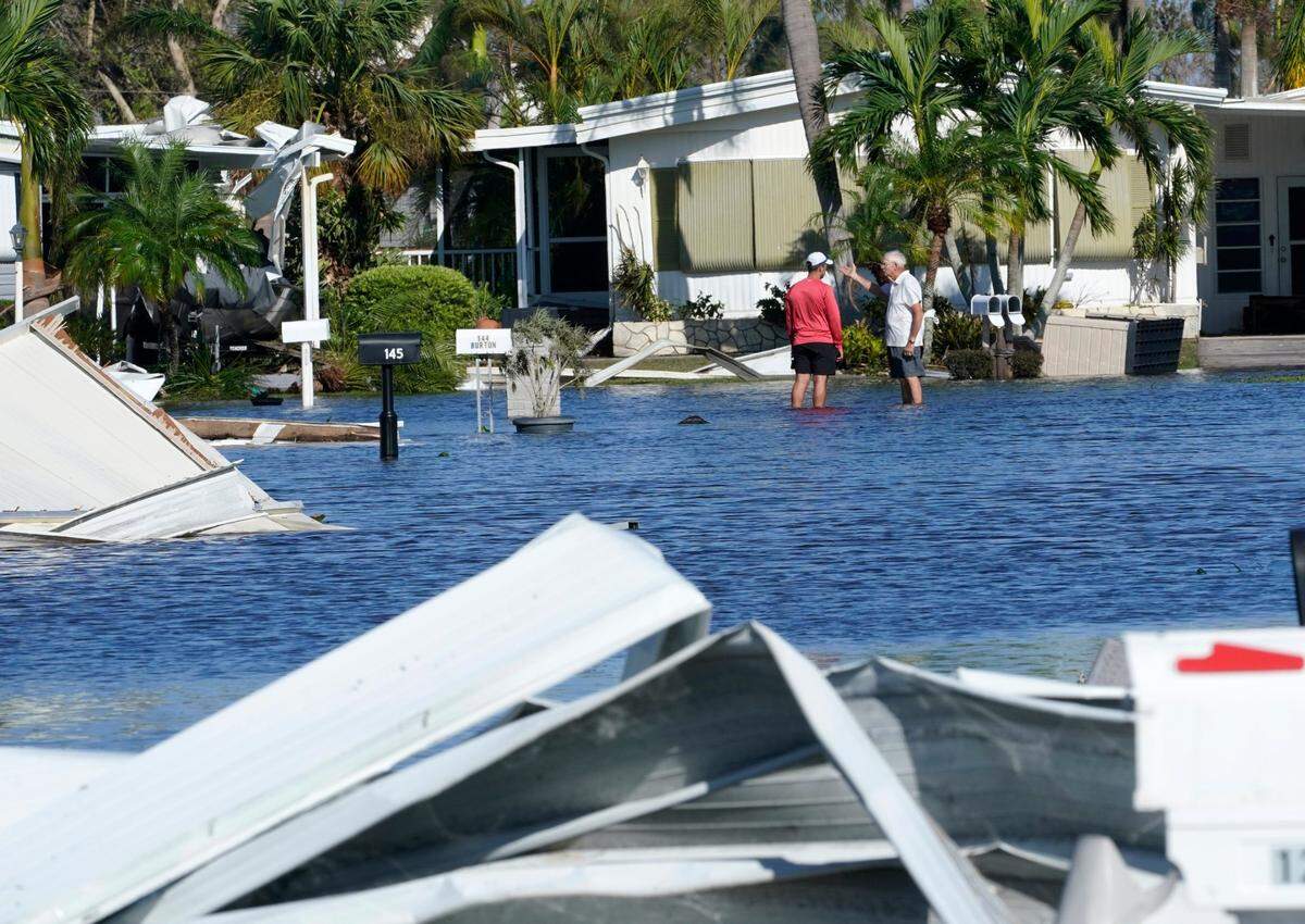 Trailer park residents talk in a flooded area after Hurricane Ian passed by Thursday, Sept. 29, 2022, in Fort Myers, Fla.