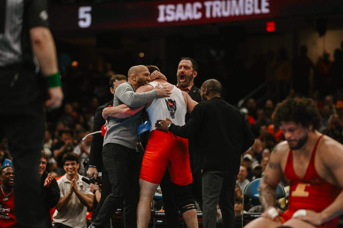 N.C. State wrestler Isaac Trumble celebrates with his coaches after winning the NCAA national championship in the heavyweight class on March 21, 2026, in Cleveland, Ohio.
