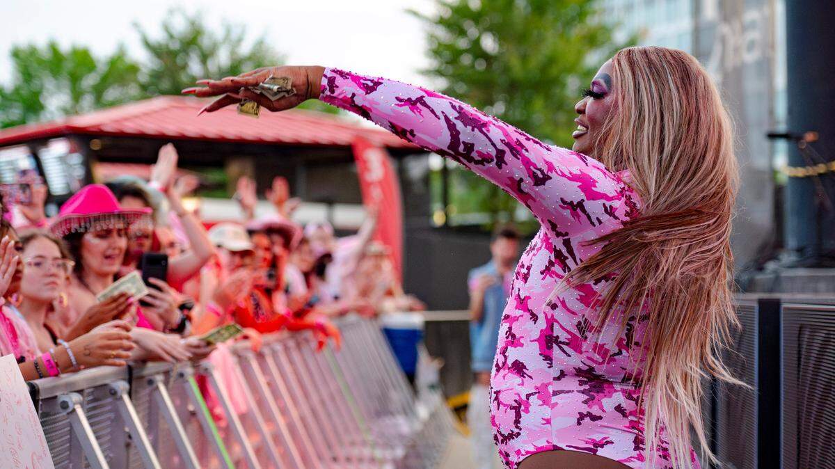 Drag Queen Erica Chanel accepts tips from the crowd during her opening performance for Chappell Roan at Red Hat Amphitheater on Wednesday, June 12, 2024. Chanel opened for Roan at an earlier tour and returned to host the and perform for the opening act in Raleigh on the 2024 Midwest Princess Tour.