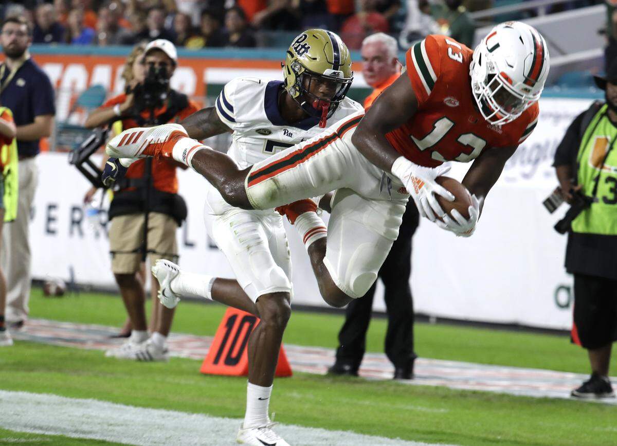 Miami running back DeeJay Dallas (13) stretches for a first down at the 4-yard-line in front of Pittsburgh defensive back Jazzee Stocker, left, during the second half of an NCAA college football game, Saturday, Nov. 24, 2018, in Miami Gardens, Fla. Miami won 24-3.