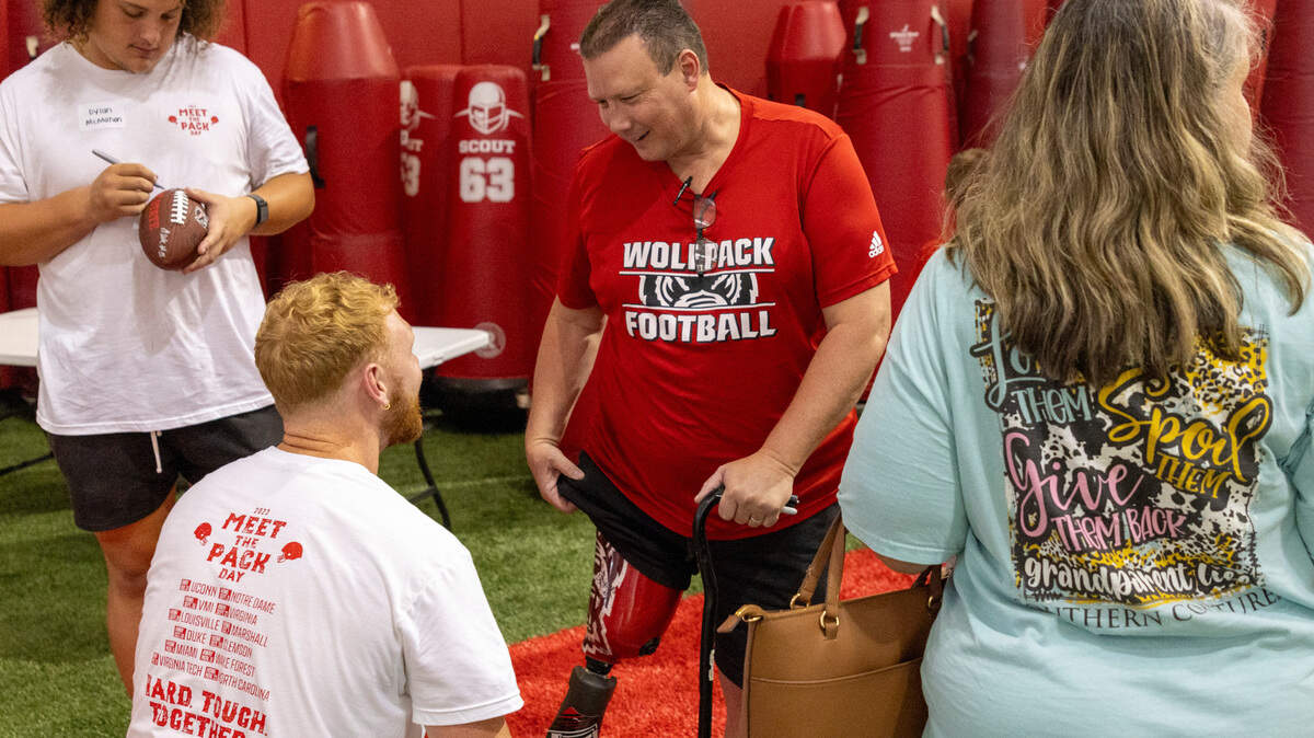 Bryan Mooring asks quarterback Brennan Armstrong to autograph his Wolfpack-themed prosthetic leg during N.C. State’s ‘Meet the Pack’ event with players and fans at the Close-King Indoor Practice Facility Saturday, Aug. 16, 2023.