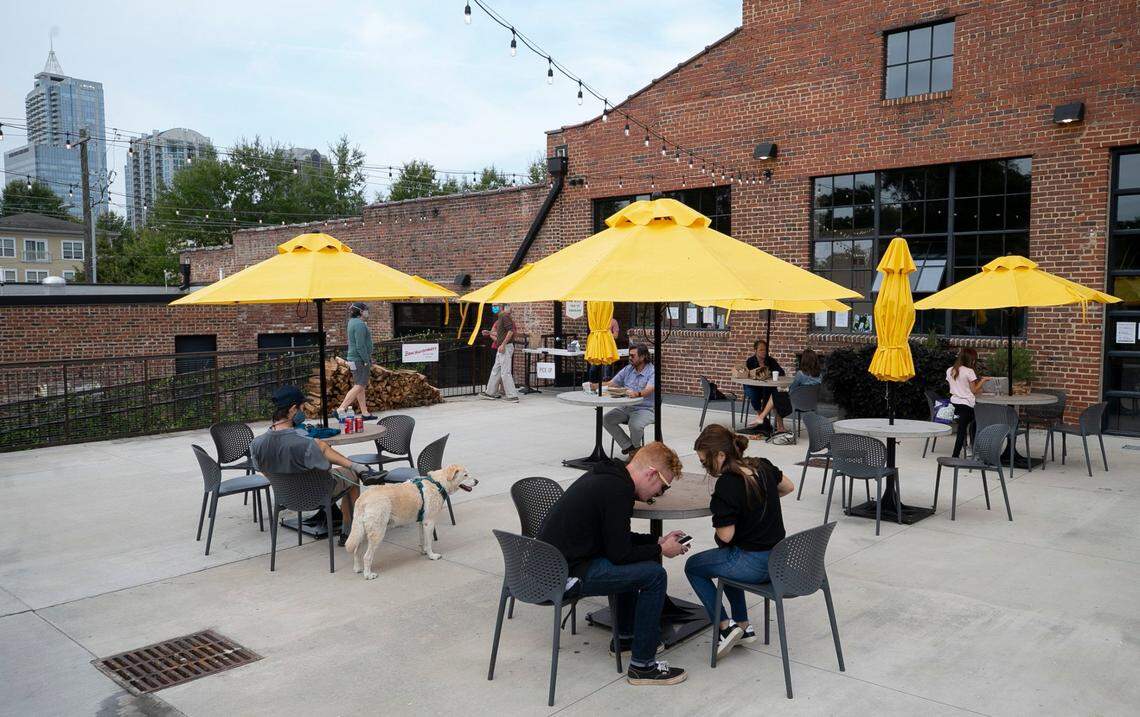 Patrons dine outside at the Transfer Co. Food Hall on E. Davie Street on Friday, October 9, 2020 in Raleigh, N.C. Cement tables are spaced out for social distancing, preventing patrons from moving tables together.