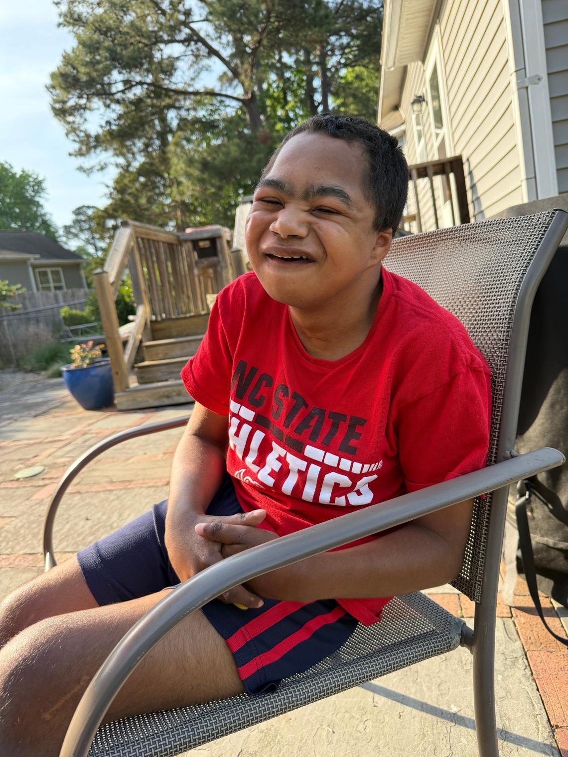 N.C. State superfan Grayson Ketchie, 14, smiles as he sits in a chair at his family home on April 29, 2025. (Dianne Ketchie/Courtesy)
