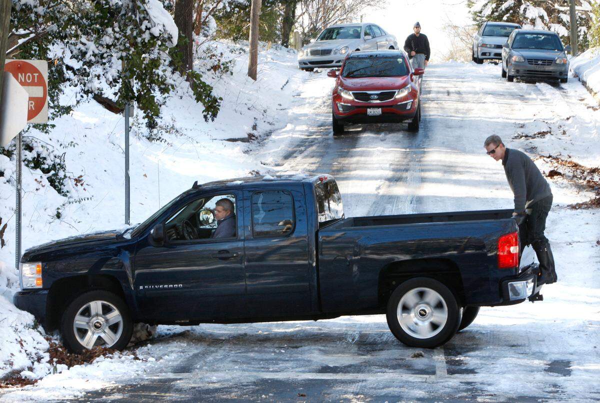 Dan Neil, right, and Nash Turley, top of frame, assist Ted Cashion, in truck, on Everett Avenue in Raleigh.