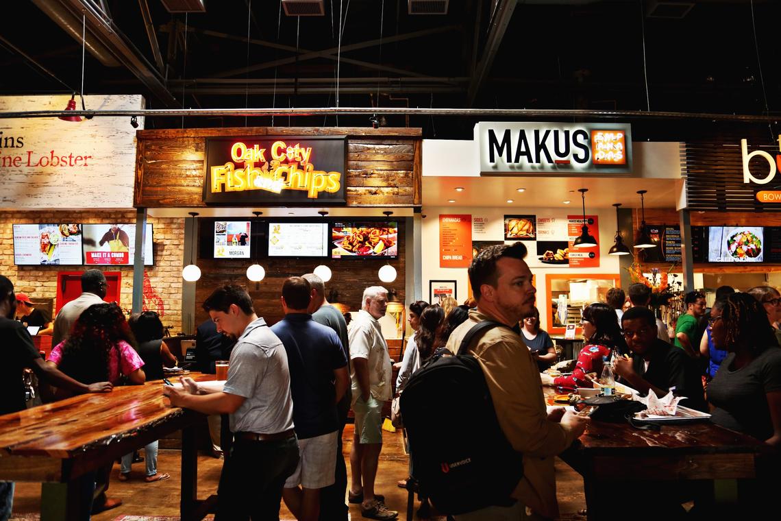 People dine at standing tables in the common area during lunch on Morgan Street Food Hall’s first day, Aug. 20, 2018, in downtown Raleigh.