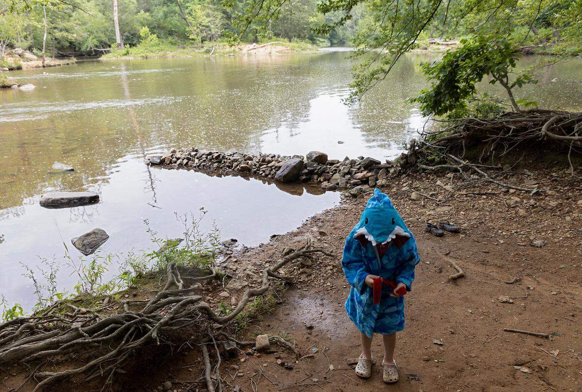 Fiona Campbell, 6, wraps up in a towel as rain begins to fall at Sennett’s Hole on the Eno River on Monday, July 3, 2023, in Durham, N.C.