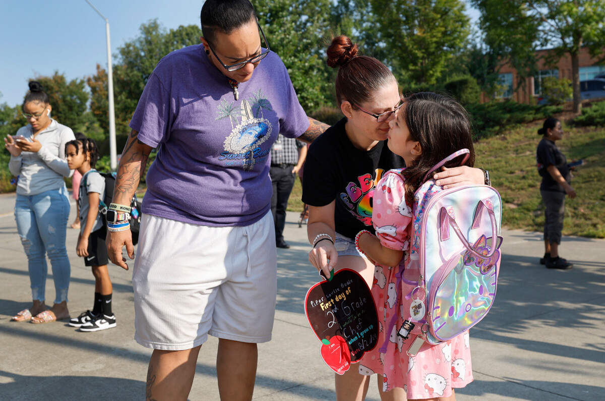 Ivy Godde giver her daughter Piper, a second grader, a kiss before the first day of school at Green Magnet Elementary School in Raleigh, N.C., Tuesday, August 27, 2024. Godde’s partner Stephanie Varela stands to the left.