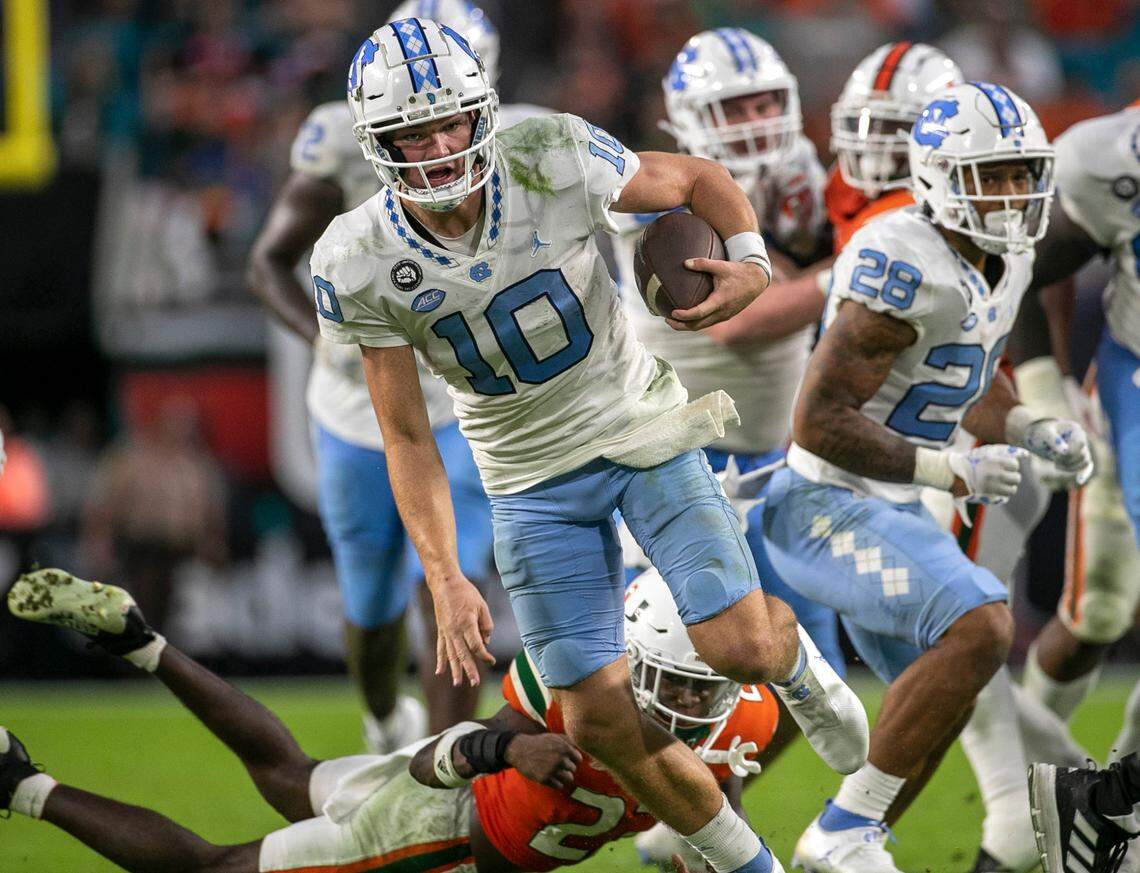 North Carolina quarterback Drake Maye (10) rushes for 11 yards in the fourth quarter ahead of Miami’s Te’Cory Couch (23) on Saturday, October 8, 2022 at Hard Rock Stadium in Miami Gardens, Florida. Maye rushed for 53 yards in the Tar Heels’ victory.
