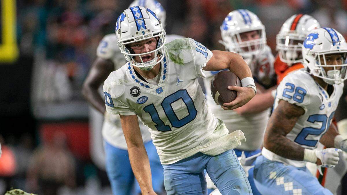 North Carolina quarterback Drake Maye (10) rushes for 11 yards in the fourth quarter ahead of Miami’s Te’Cory Couch (23) on Saturday, October 8, 2022 at Hard Rock Stadium in Miami Gardens, Florida. Maye rushed for 53 yards in the Tar Heels’ victory.