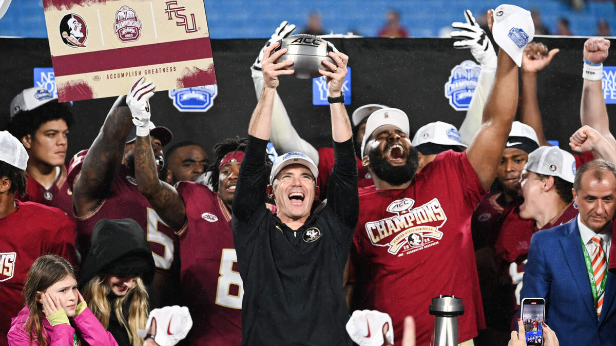 Florida State Seminoles head coach Mike Norvell raises the ACC Championship trophy with his players after their victory over Louisville at Bank of America Stadium in December 2023.