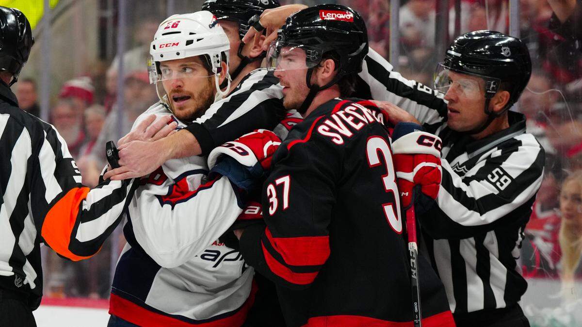 Carolina Hurricanes right wing Andrei Svechnikov (37) and Washington Capitals center Nic Dowd (26) grab hold of each other during the first period at Lenovo Center.