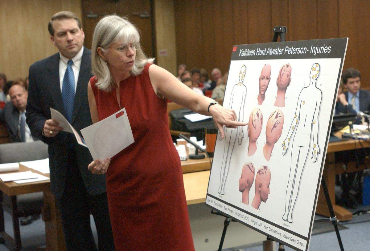 Dr. Deborah Radisch, MD, associate chief medical examiner for the state of North Carolina indicates to the Peterson jury Thursday am the approximate locations and severity of head injuries to Kathleen Peterson on an artist’s rendering while also holding graphic autopsy photographs along with prosecutor Jim Hardin, left. Dr. Radisch was on the witness stand all day for the 40th day of the Michael Peterson murder trial in Durham.