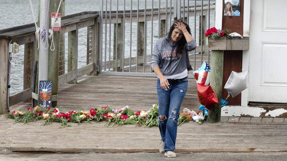 A woman walks away after placing balloons at a memorial for victims of a shooting at the American Fish Company in Southport, N.C., Sunday afternoon, Sept. 28, 2025. A man in a boat shot into the popular nightspot along the water Saturday night, killing three people.