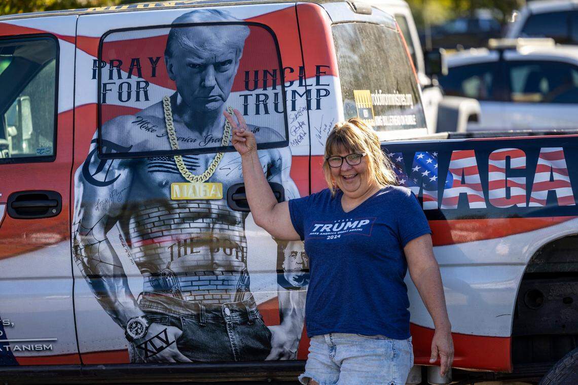 A supporter of former President Donald Trump poses with a pickup truck outside Minges Coliseum in Greenville prior to a rally on Monday, Oct. 21, 2024. With two weeks until Election Day, Trump went on a three-city tour, in which Trump will also see the destruction caused by Hurricane Helene in Asheville and speak at a faith conference in Concord.
