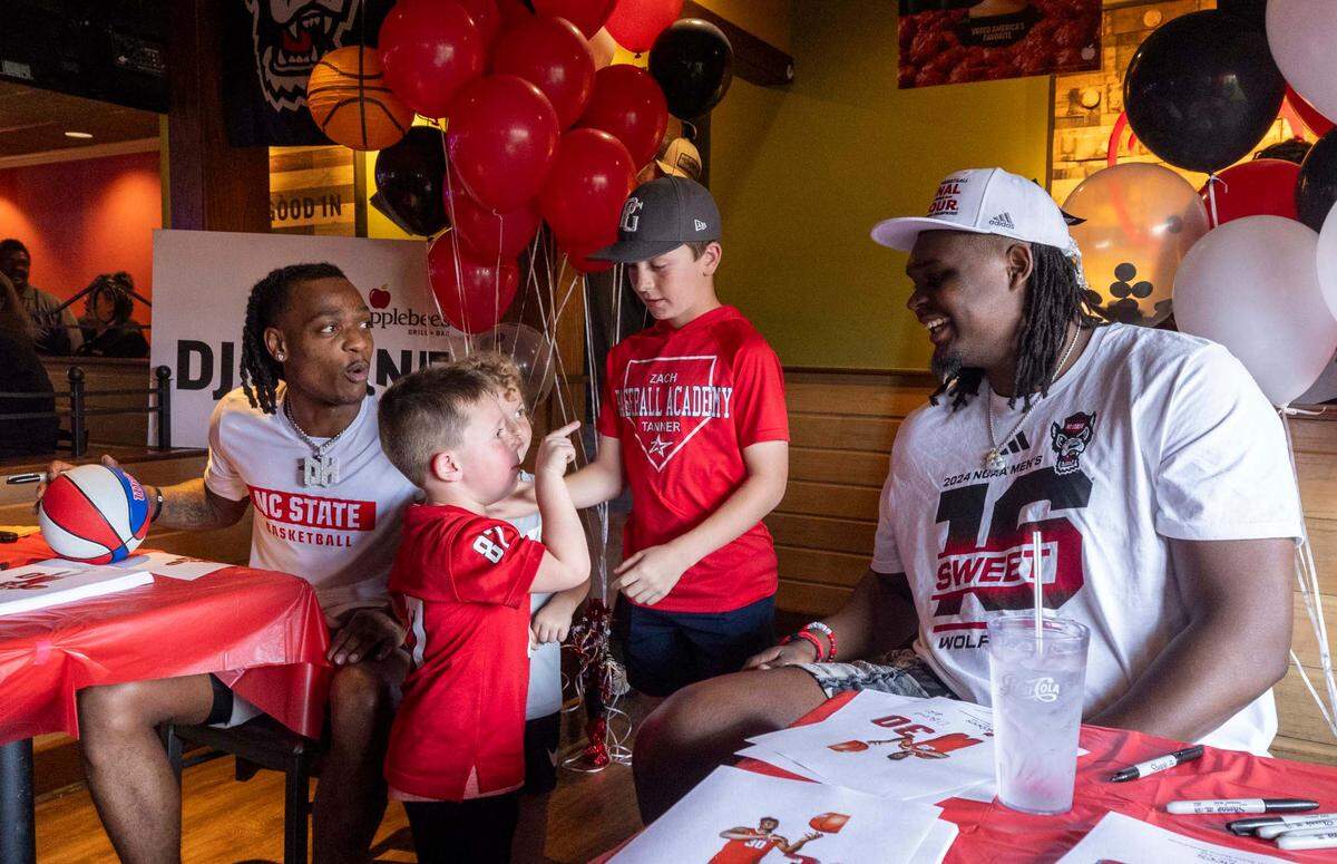 Five-year-old Walker Merritt and NC State’s DJ Burns Jr. share a moment as Burns and DJ Horne, left, sign hundreds of autographs at the Triangle Town Center Applebee’s in Raleigh on Tuesday, April 2, 2024 ahead of the Wolfpack’s Final Four game on Saturday.