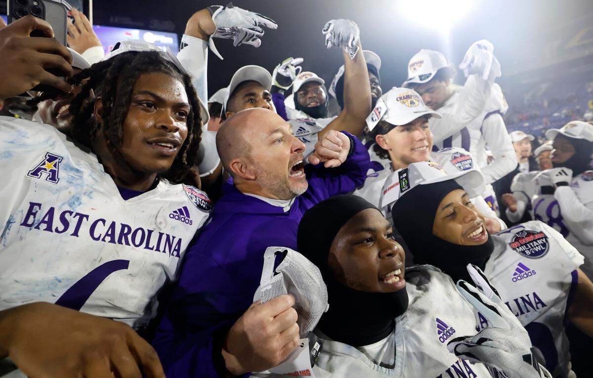East Carolina head coach Blake Harrell gives the pirate hook as he and the team celebrate ECU’s 26-21 victory over N.C. State in the Military Bowl at Navy-Marine Corps Memorial Stadium in Annapolis, Md., Saturday, Dec. 28, 2024.