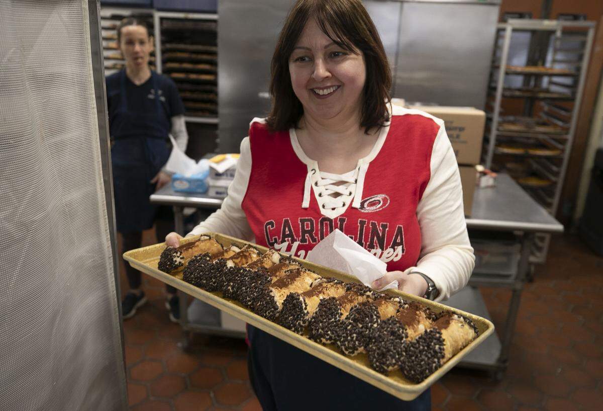 Mike’s Pastry employee Val Sinani, sporting a Carolina Hurricanes shirt, brings a fresh tray of cannolis from the kitchen to the serving counter on Thursday, May 9, 2019 in Boston, Mass.