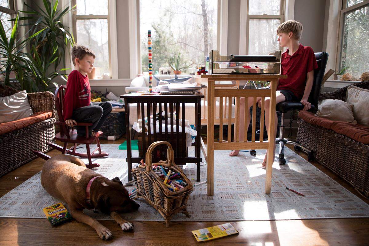 Liam, 8, left, and Alex Potts, 11, right, sit in Liam’s new classroom next to their family’s kitchen on the afternoon of Thursday, March 19, 2020. Their mom, Allison Potts, is able to work from home with newly flexible hours to make sure her children continue to learn despite schools and childcare centers remaining closed until further notice to curb the spread of COVID-19.