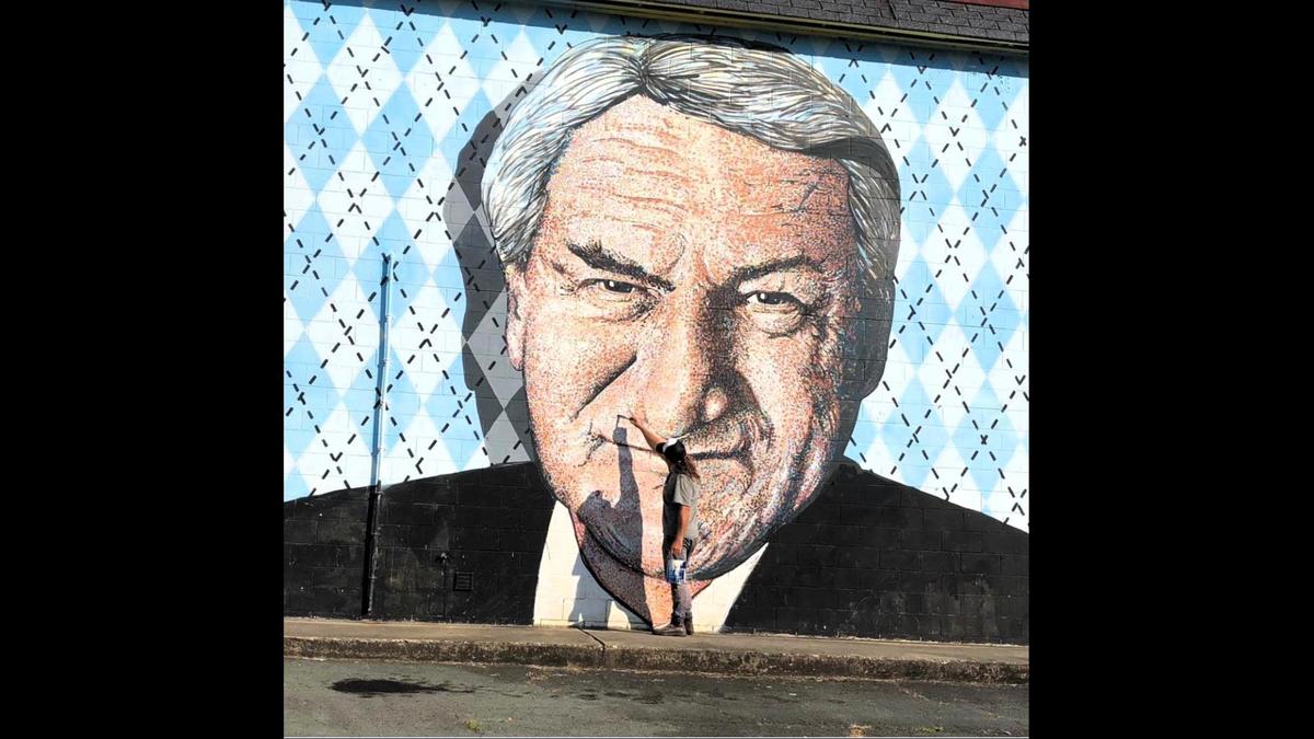 Artist Scott Nurkin puts the final touches on a mural honoring UNC basketball coach Dean Smith in 2015. The mural at the corner of Smith Level Road and U.S. 15-501 will be torn down to make way for a new gas station and convenience store.