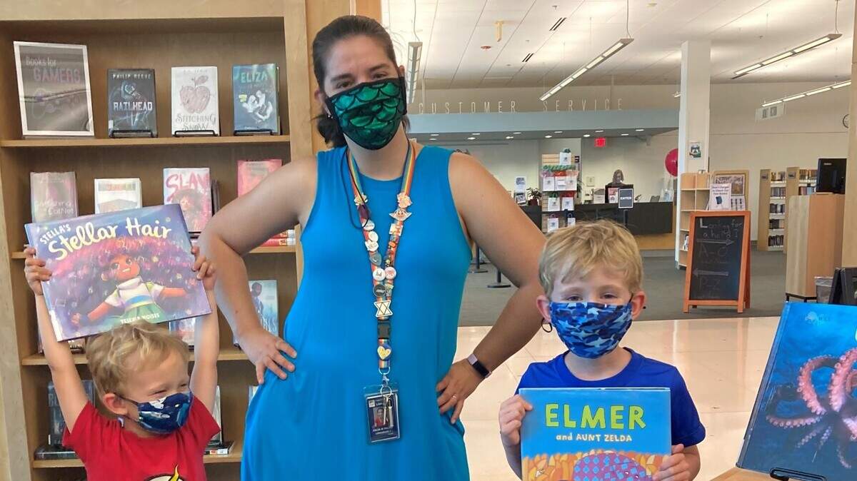 Sam and David Klingenberg celebrate their in-person return to the library with Wake County Youth Services Librarian Julia Palko at the Village Regional Branch.