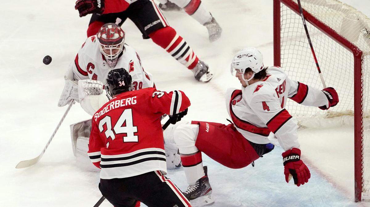 Carolina Hurricanes’ Haydn Fleury (4) trips backward over goaltender Alex Nedeljkovic as Chicago Blackhawks’ Carl Soderberg looks for a rebound during the second period of an NHL hockey game Tuesday, March 30, 2021, in Chicago. (AP Photo/Charles Rex Arbogast)