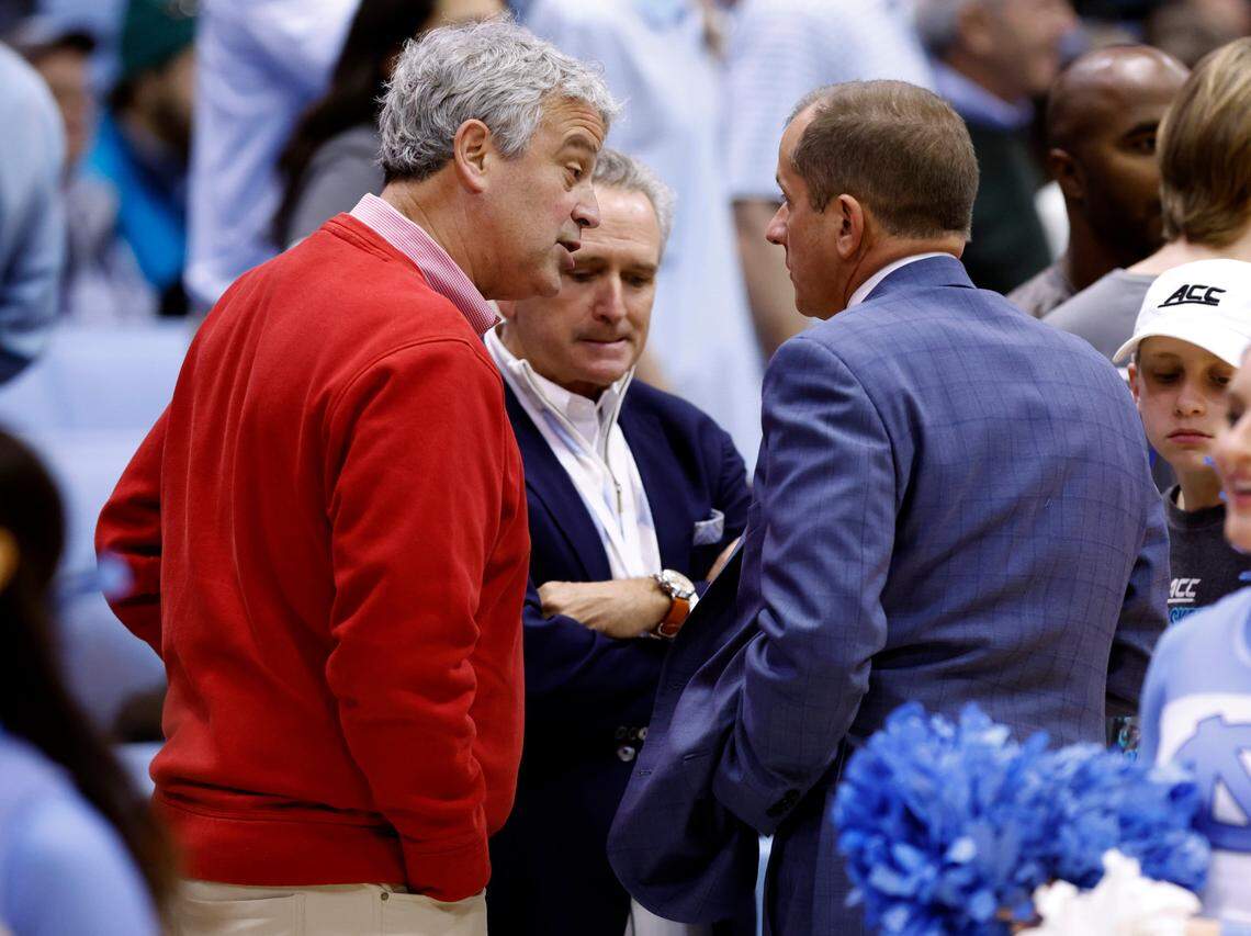N.C. State athletic director Boo Corrigan, left, and North Carolina athletic director Bubba Cunningham, center, talk with ACC Commissioner Jim Phillips before N.C. State’s game against UNC at the Smith Center in Chapel Hill, N.C., on Jan. 21, 2023.