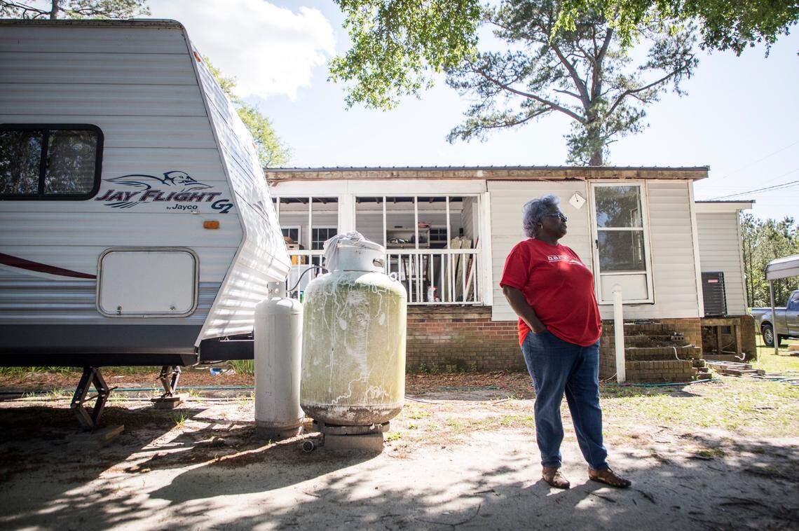 In a 2020 photo, Jacqueline Hand stands outside her home next to the travel trailer she and her family were living in near Burgaw, N.C.. Hand’s home was inundated with flood waters during Hurricane Florence and she and her family had yet to move back in almost two years later. Delays in permitting and difficulty securing contractors prevented repairs for almost a year, therefore volunteer groups were a huge help. 