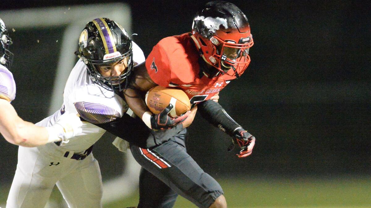 Tharius Suggs, right, of Middle Creek carries the ball against the Golden Hawks’ defense. The Holly Springs Golden Hawks visited the Middle Creek Mustangs in a high school football game on October 18, 2019.