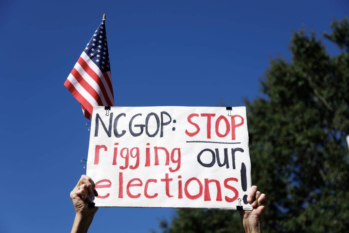 A participant holds a sign aloft during a rally held by the North Carolina Democratic Party outside the State Capitol on Tuesday to protest the GOP-led legislature’s new congressional redistricting proposal. 