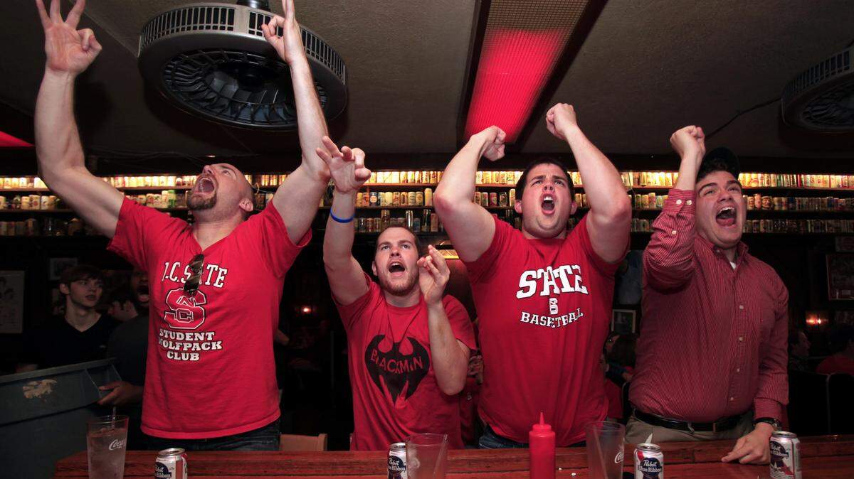 At The Players’ Retreat, a sports bar in Raleigh, N.C. State fans, from left, Joe Zaborowski, Brian Schilling, Joe Kasperski and Matt Kasperski, celebrate the Wolfpack’s 66-63 victory over Georgetown in the third round of the NCAA Tournament Sunday, March 18, 2012.