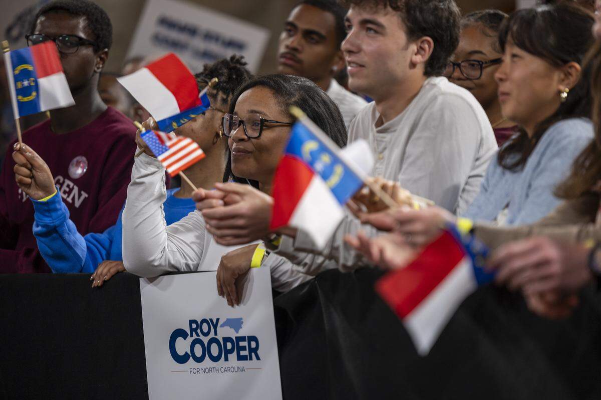 Supporters hold North Carolina flags while listening to former Gov. Roy Cooper speak during a “Make Stuff Cost Less” campaign rally on Thursday, April 9, 2026, at Bay 7 in Durham’s American Tobacco Campus. Cooper faces former Republican National Committee Chairman Michael Whatley in the race for U.S. Senate. Both are vying to replace Sen. Thom Tillis, a Republican from Huntersville, who is retiring at the end of his term.