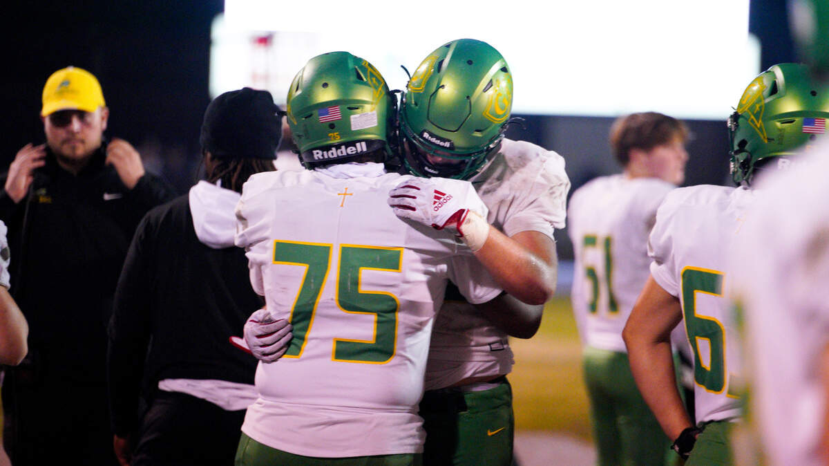 Cardinal Gibbons lineman Ethan Ganao (75) hugs a teammate in the closing minutes of the Crusaders’ NCHSAA 4A East regional final against Hoggard in Wilmington, NC, on Dec. 1, 2023. Hoggard won, 41-20.