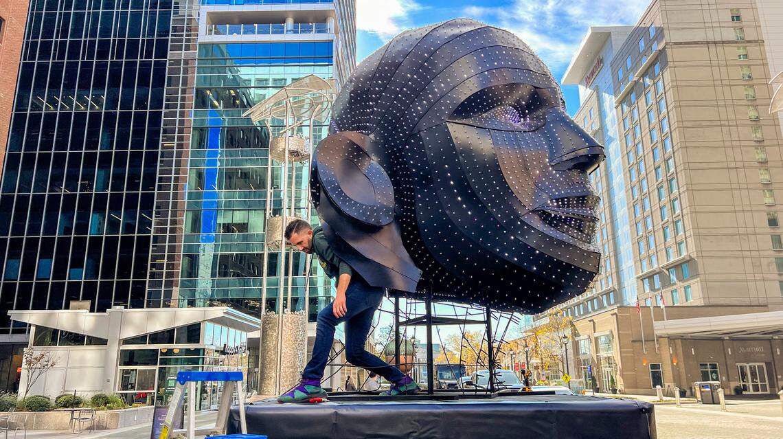 Scott Hallock helps install part of the Limelight Talking Heads installation on City Plaza in downtown Raleigh Thursday, Nov. 30, 2023. The art installation is the headliner of this year’s Illuminate Art Walk.