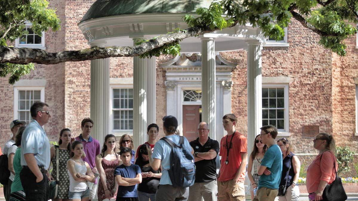 A tour group of parents, future students and family members learn the history of UNC’s Old Well on the Chapel Hill campus. Now, campuses have limited visitors due to coronavirus concerns. 