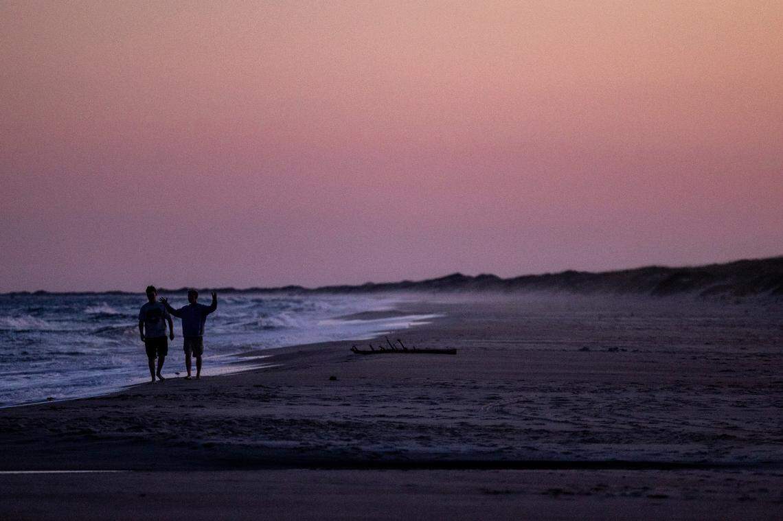 Beachgoers walk along the Cape Hatteras National Seashore in Ocracoke as the sun sets Tuesday, May 17, 2022.