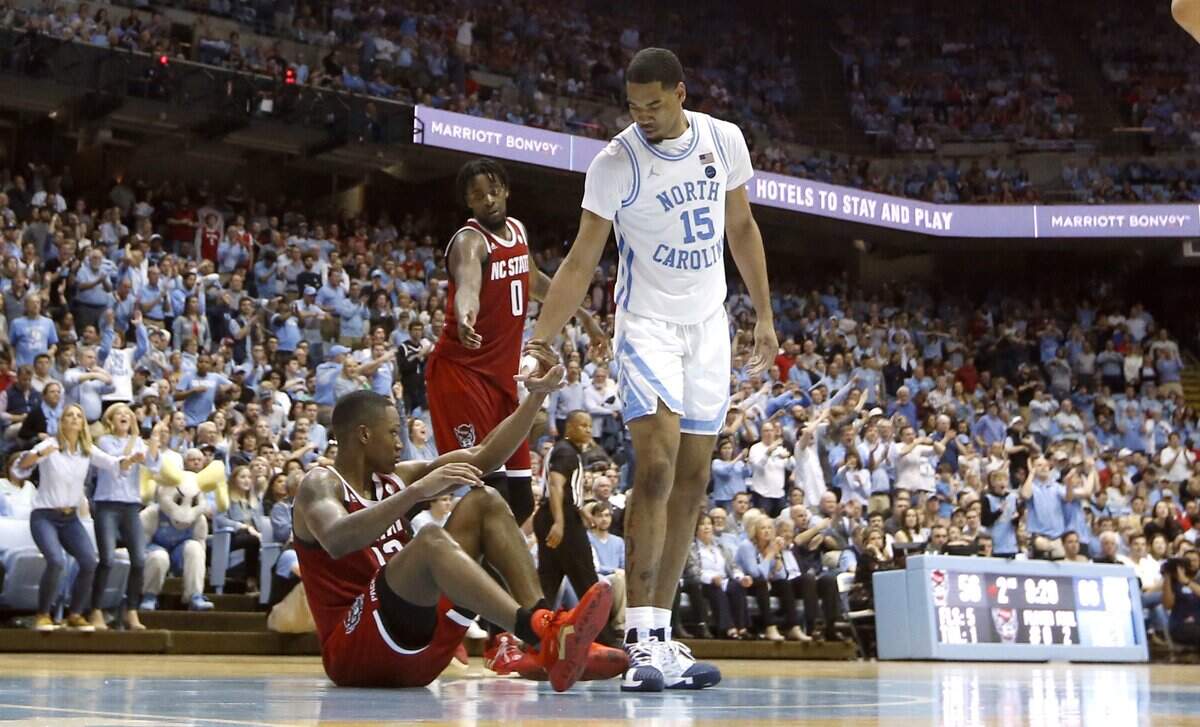 UNC’s Garrison Brooks (15) helps up N.C. State’s C.J. Bryce (13) after he fell and turned the ball over during North Carolina’s 85-79 victory over N.C. State at the Smith Center in Chapel Hill, N.C., Tuesday, Feb. 25, 2020.