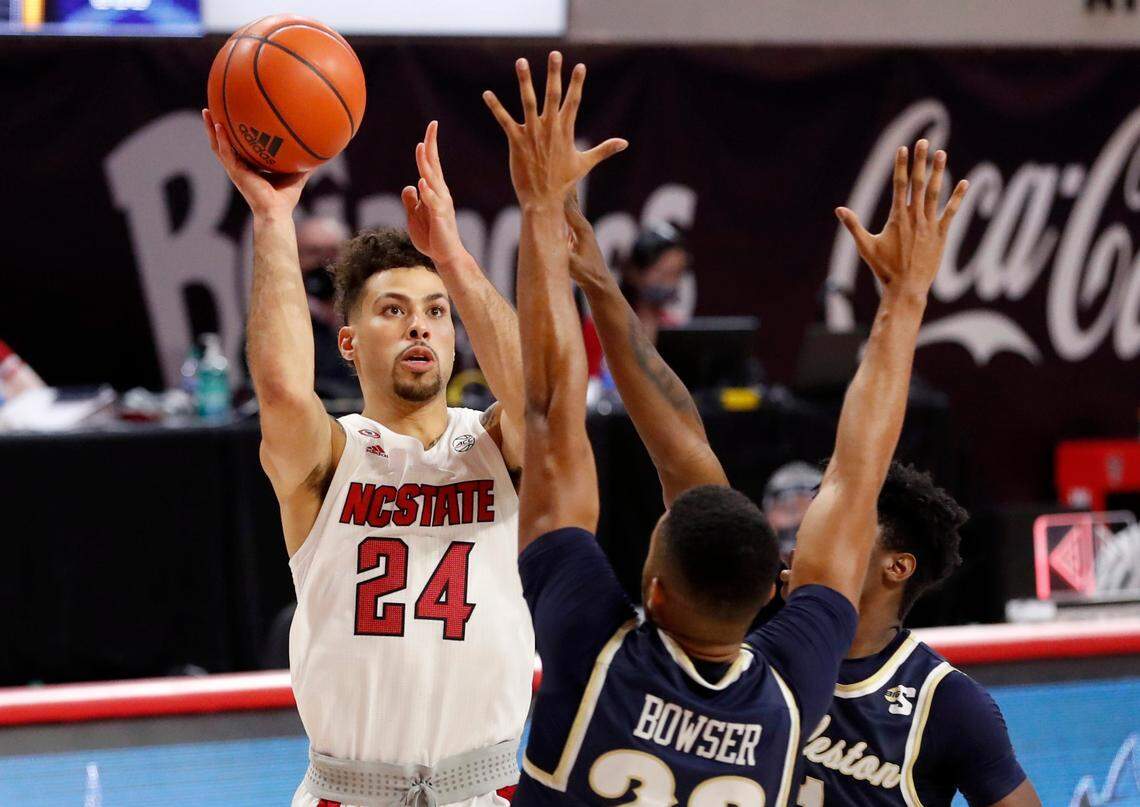 N.C. State’s Devon Daniels (24) shoots as Charleston Southern’s Sadarius Bowser (22) and Ja’Quavian Florence (11) defend during the second half of N.C. State’s 95-61 victory over Charleston Southern in the Wolfpack Invitational at Reynolds Coliseum in Raleigh, N.C., Wednesday, Nov. 25, 2020.
