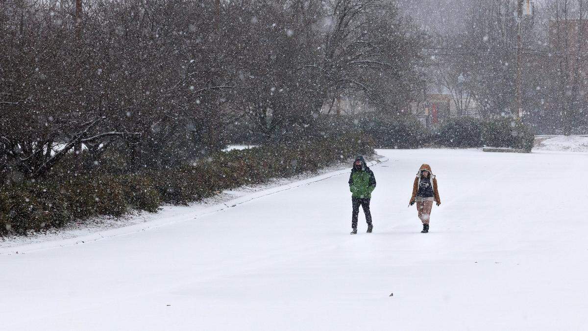 People walk through a snow-covered parking lot in downtown Durham on Saturday, Jan. 31, 2026.