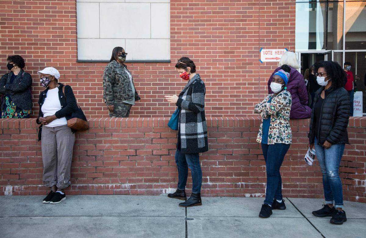 Durham County voters wait in line outside the Turner Law Building at N.C. Central University in Durham, N.C. to cast their votes on the first day of early voting, Thursday, Oct. 15, 2020.