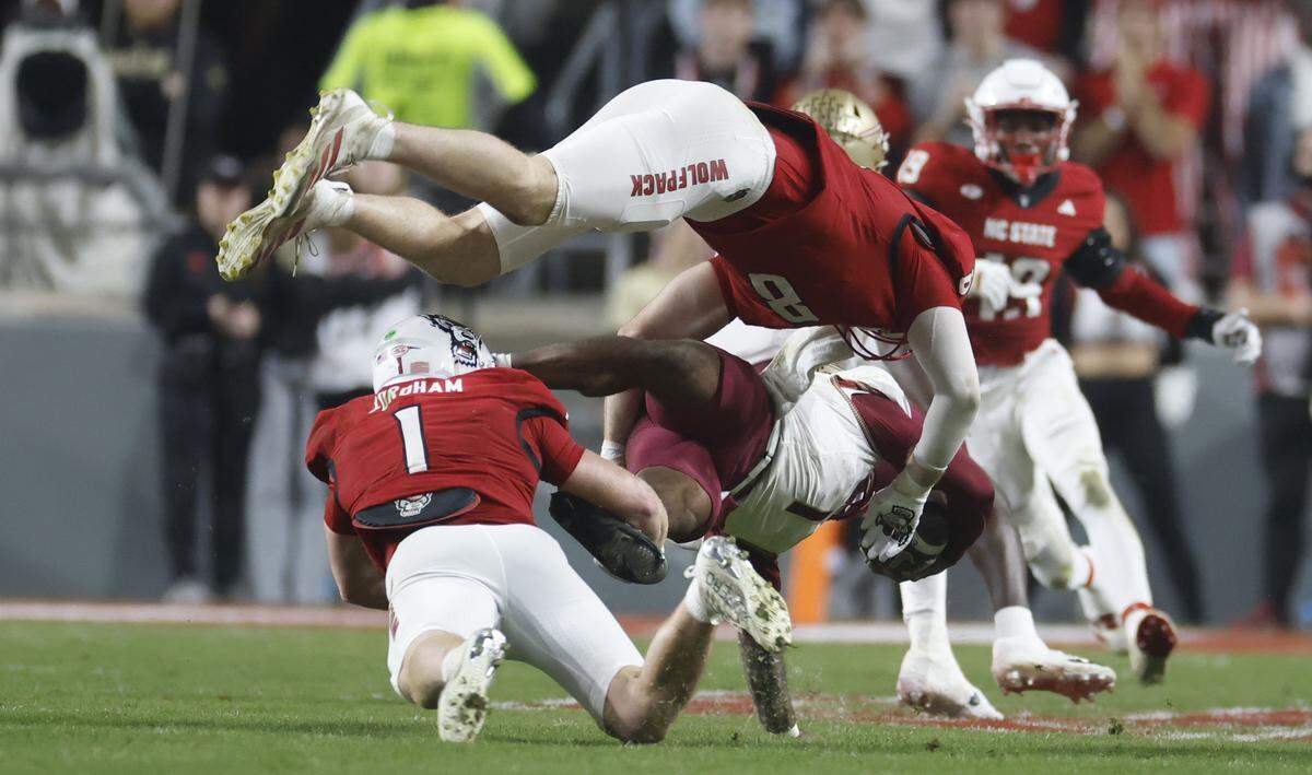 N.C. State’s Caden Fordham (1) and Cian Slone (8) tackle Florida State quarterback Tommy Castellanos (1) during the first half of N.C. State’s game against Florida State at Carter-Finley Stadium in Raleigh, N.C., Friday, Nov. 21, 2025.