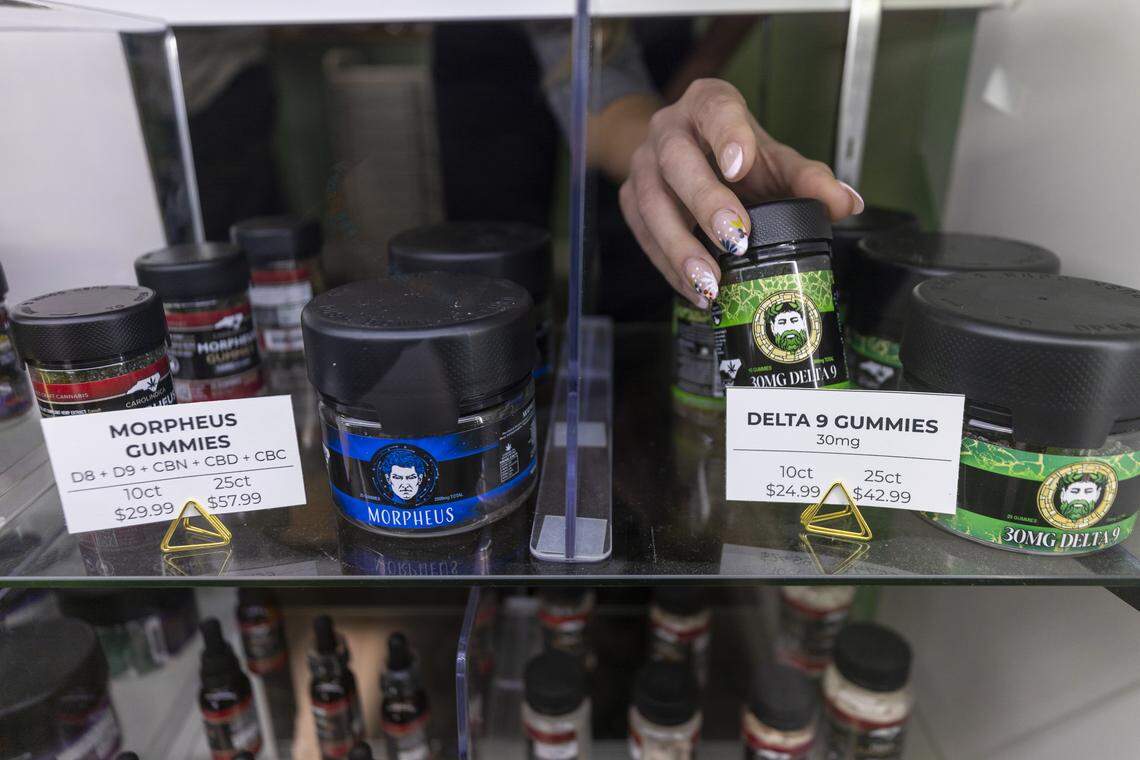 An employee at the North Carolina hemp retailer and manufacturer Carolindica retrieves a container of hemp infused gummies from a display case in the company’s Raleigh store on Tuesday, Nov. 25, 2025. A new federal provision could remove most hemp products from shelves, threatening North Carolina shops, growers and supply chains as businesses increase lobbying efforts.