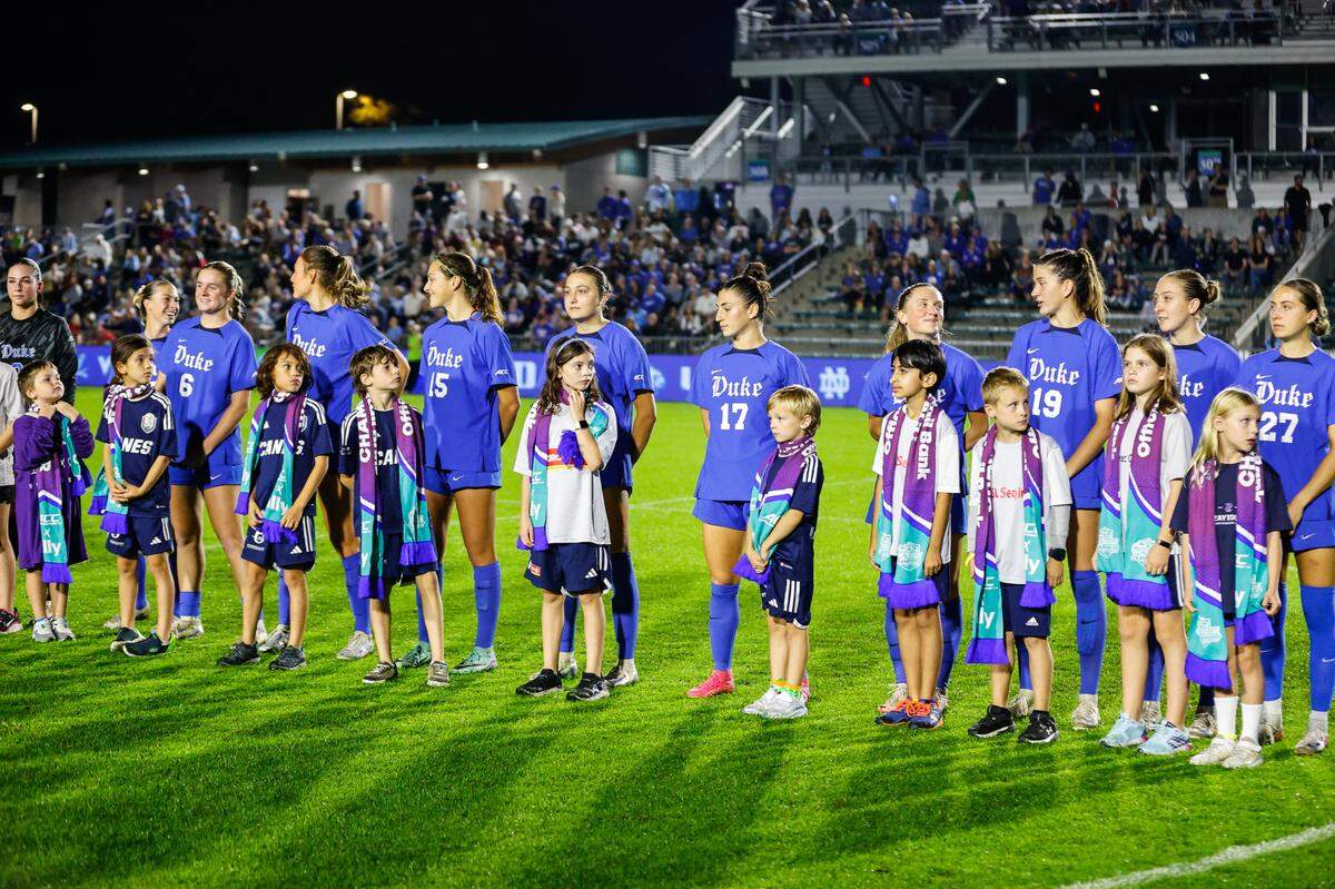 Duke’s players, including former UNC Tar Heels player Mia Oliaro (15), stand with youth players, prior to an ACC Women’s Soccer Championship semifinal game against UNC at Cary on Thursday Nov. 7th, 2024.